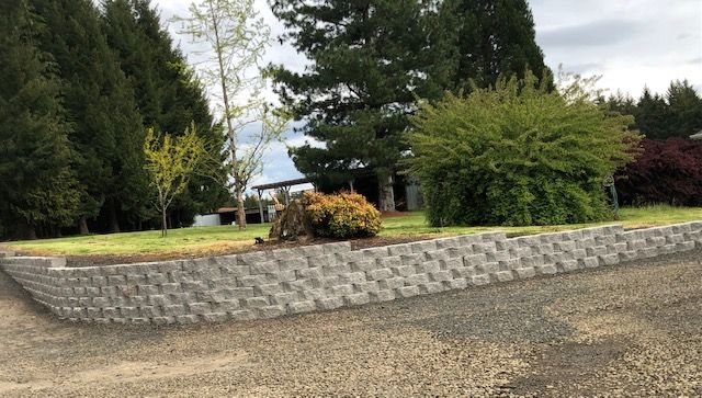 A new stone retaining wall with sod and landscaping built around it